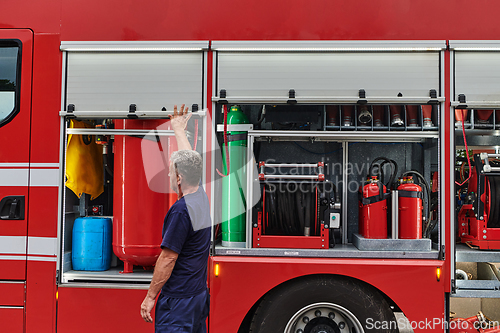 Image of A dedicated firefighter preparing a modern firetruck for deployment to hazardous fire-stricken areas, demonstrating readiness and commitment to emergency response