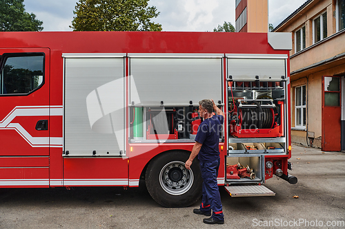 Image of A dedicated firefighter preparing a modern firetruck for deployment to hazardous fire-stricken areas, demonstrating readiness and commitment to emergency response