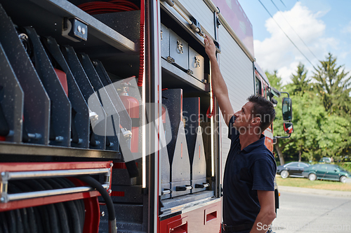 Image of A dedicated firefighter preparing a modern firetruck for deployment to hazardous fire-stricken areas, demonstrating readiness and commitment to emergency response