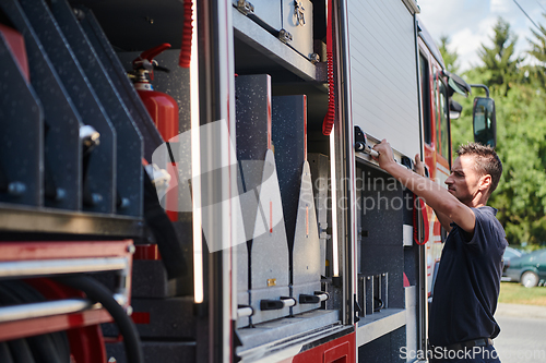 Image of A dedicated firefighter preparing a modern firetruck for deployment to hazardous fire-stricken areas, demonstrating readiness and commitment to emergency response