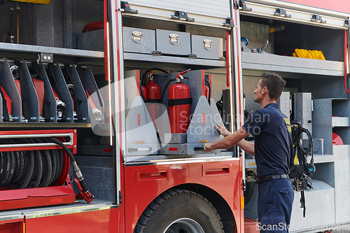 Image of A dedicated firefighter preparing a modern firetruck for deployment to hazardous fire-stricken areas, demonstrating readiness and commitment to emergency response