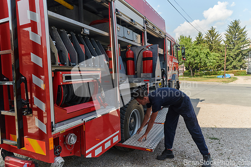 Image of A dedicated firefighter preparing a modern firetruck for deployment to hazardous fire-stricken areas, demonstrating readiness and commitment to emergency response