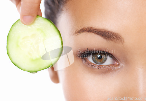 Image of Woman, face and cucumber by eyes in beauty, facial or spa treatment on a white studio background. Closeup of female person and natural organic vegetable for anti aging benefits in health and wellness