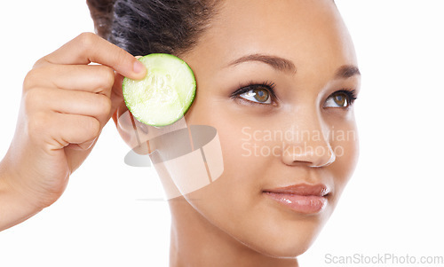 Image of Woman, face and cucumber by eyes in skincare, beauty or facial and spa treatment against a white studio background. Closeup of female person or model with natural organic vegetables for wellness