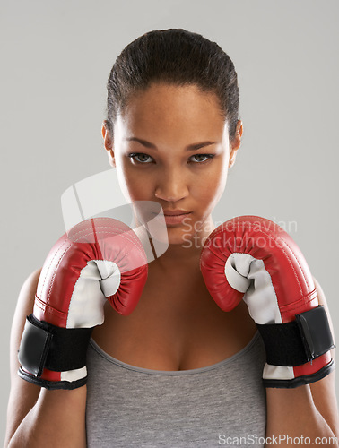 Image of Serious woman, portrait and professional boxer ready for fight or competition against a gray studio background. Female person with boxing gloves for self defense, power or challenge in sports fitness