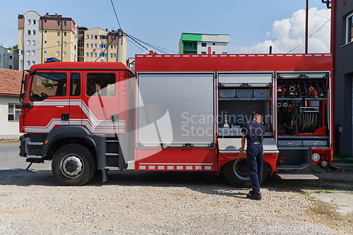 Image of A dedicated firefighter preparing a modern firetruck for deployment to hazardous fire-stricken areas, demonstrating readiness and commitment to emergency response