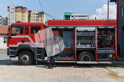 Image of A dedicated firefighter preparing a modern firetruck for deployment to hazardous fire-stricken areas, demonstrating readiness and commitment to emergency response