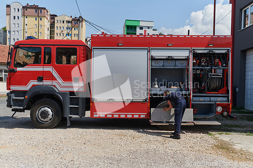 Image of A dedicated firefighter preparing a modern firetruck for deployment to hazardous fire-stricken areas, demonstrating readiness and commitment to emergency response