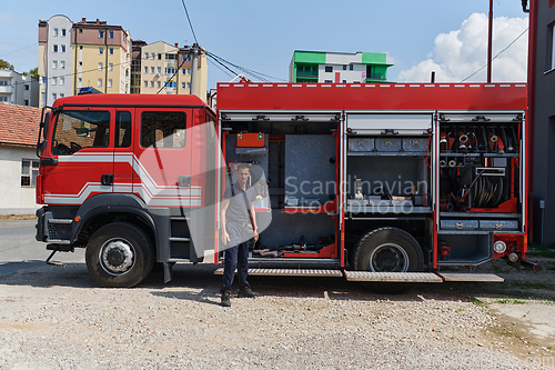 Image of A dedicated firefighter preparing a modern firetruck for deployment to hazardous fire-stricken areas, demonstrating readiness and commitment to emergency response