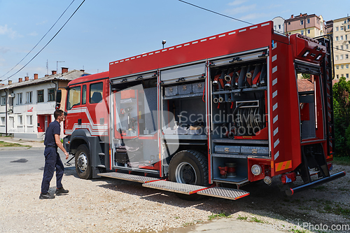 Image of A dedicated firefighter preparing a modern firetruck for deployment to hazardous fire-stricken areas, demonstrating readiness and commitment to emergency response