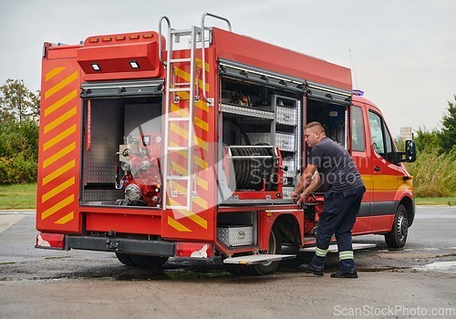 Image of A dedicated firefighter preparing a modern firetruck for deployment to hazardous fire-stricken areas, demonstrating readiness and commitment to emergency response