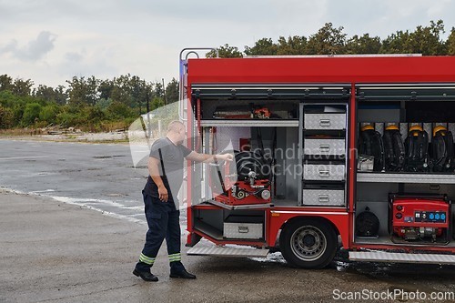 Image of A dedicated firefighter preparing a modern firetruck for deployment to hazardous fire-stricken areas, demonstrating readiness and commitment to emergency response