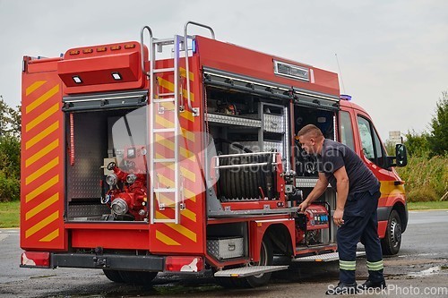 Image of A dedicated firefighter preparing a modern firetruck for deployment to hazardous fire-stricken areas, demonstrating readiness and commitment to emergency response