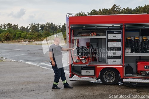 Image of A dedicated firefighter preparing a modern firetruck for deployment to hazardous fire-stricken areas, demonstrating readiness and commitment to emergency response