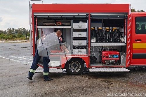 Image of A dedicated firefighter preparing a modern firetruck for deployment to hazardous fire-stricken areas, demonstrating readiness and commitment to emergency response