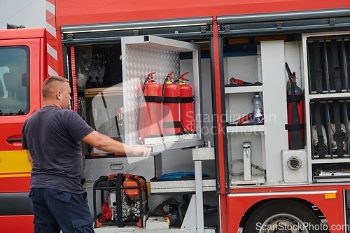 Image of A dedicated firefighter preparing a modern firetruck for deployment to hazardous fire-stricken areas, demonstrating readiness and commitment to emergency response