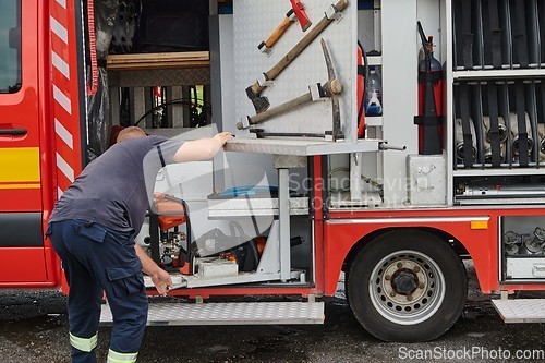 Image of A dedicated firefighter preparing a modern firetruck for deployment to hazardous fire-stricken areas, demonstrating readiness and commitment to emergency response