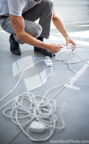 Image of Hands, man and electrician plug connection, power and electricity in office. Cord, wire and cable on floor, socket and energy of worker, professional or employee charging on technology in workplace