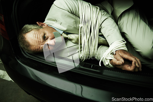 Image of Car boot, hostage or portrait of business man with tape, rope and kidnap danger in parking lot. Fear, stress and face of male victim in a vehicle trunk with anxiety, horror or crime, scared or ransom