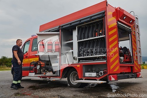 Image of A dedicated firefighter preparing a modern firetruck for deployment to hazardous fire-stricken areas, demonstrating readiness and commitment to emergency response