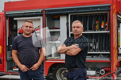 Image of A skilled and dedicated professional firefighting team proudly poses in front of their state of the art firetruck, showcasing their modern equipment and commitment to ensuring public safety.