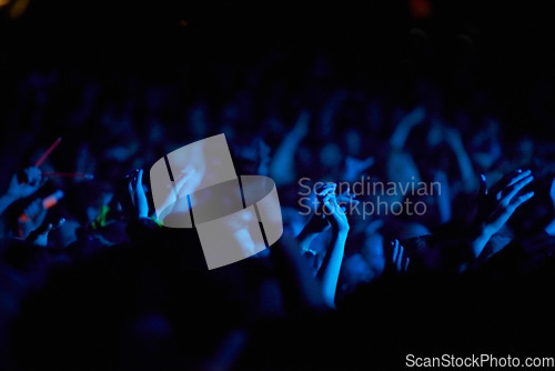 Image of Concert, hands and audience for music with blue lights, neon and night festival, concert or psychedelic party. Crowd with arms raised with nightlife and rave or techno event for new year holiday