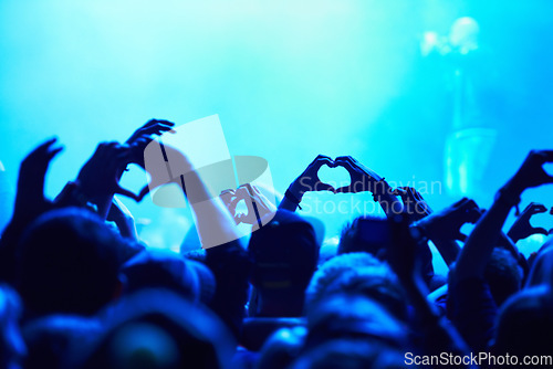 Image of People, heart hands and crowd with blue light for music concert for love, support and care of artist. Audience, fans and nightlife together with gesture for unity, community or solidarity at festival