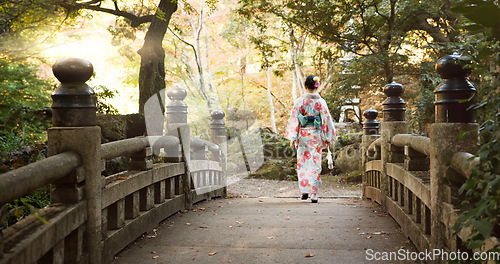 Image of Bridge, culture and Japanese woman in park for wellness, fresh air and walking in nature. Travel, traditional and person in indigenous clothes, fashion and kimono outdoors for zen, calm and peace