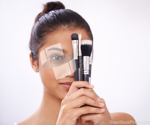 Image of Cosmetics, brushes and woman cover eyes in studio for beauty, foundation and makeup on a white background. Young model, artist or person with skincare, application tools or product for face coverage