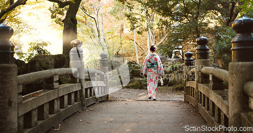 Image of Bridge, walking and Japanese woman in park for wellness, fresh air and relaxing in nature. Travel, traditional and person in indigenous clothes, fashion and kimono outdoors for zen, calm and peace