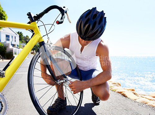 Image of Man, bicycle and tyre puncture or road change for safe transport, performance or repair. Male person, cyclist and ocean for gear improvement or endurance for triathlon training, sport or practice