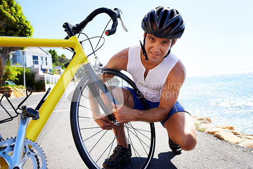 Image of Man, portrait and wheel repair on road for safe cycling transport, performance or puncture. Male person, tyre and ocean for gear improvement or endurance for triathlon training, sport or practice