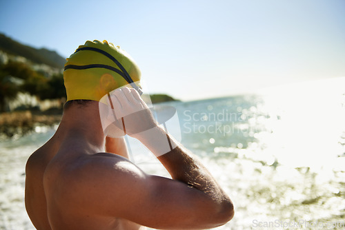 Image of Sea, beach and man for swimmer exercise, nature workout or outdoor practice in ocean, sea or water waves. Swimwear, swimming cap and athlete prepare to start challenge, fitness performance or cardio