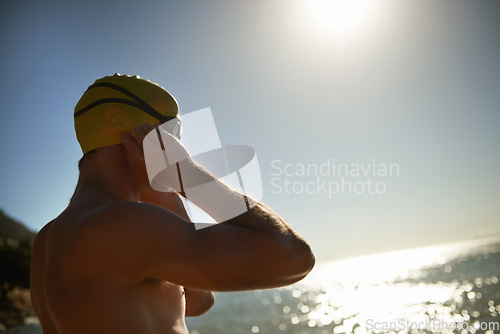 Image of Sea, beach sunset and man for swimmer exercise, workout or outdoor training in ocean, nature or water. Mockup space, swimming cap and athlete ready to start challenge, fitness competition or cardio