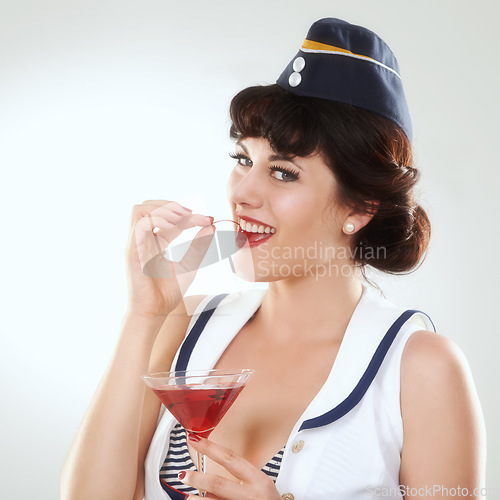 Image of Portrait, stewardess and happy woman with alcohol to drink in studio isolated on white background. Face, martini cocktail glass and air hostess eating cherry, travel or vintage pin up girl on journey