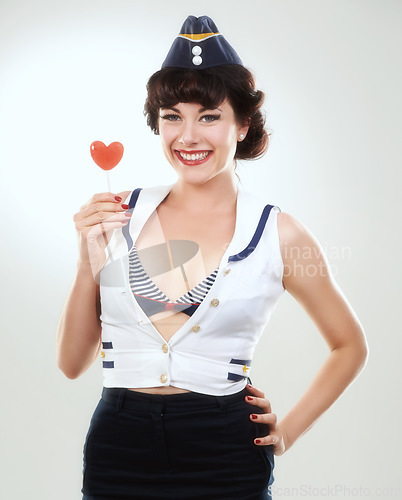 Image of Portrait, smile of woman and sailor with lollipop in studio isolated on a white background. Face, candy and happy air hostess with sugar food, heart sweets and travel dessert for vintage pin up girl