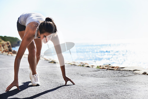 Image of Woman, fitness and starting line by beach for running, workout or sprint in outdoor exercise. Active young female person getting ready for run, lap or cardio training on asphalt road by ocean coast