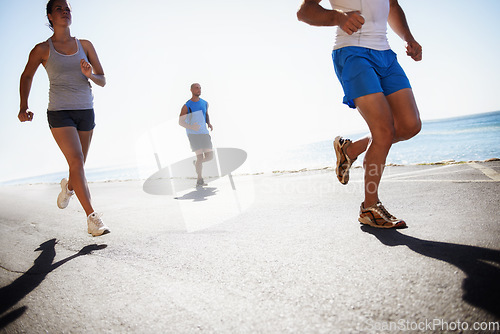 Image of People, team and running at beach for cardio, fitness or outdoor workout together on asphalt or road. Athletic group or runners in sports, training exercise or street on sunny day by the ocean coast