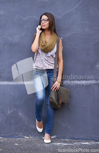 Image of Woman, phone call or communication by wall for talking, gossip or networking in conversation. Glasses, relax or profile of female person for speaking chat, news or trendy urban fashion in discussion