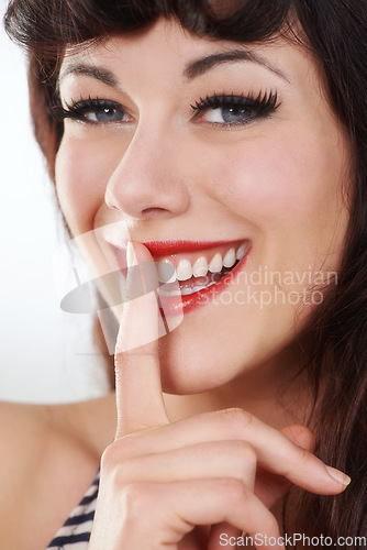 Image of Portrait, smile and woman with finger for secret, privacy or shush emoji in studio isolated on a white background. Face, happy girl and lips to whisper in silence, quiet or confidential hand gesture
