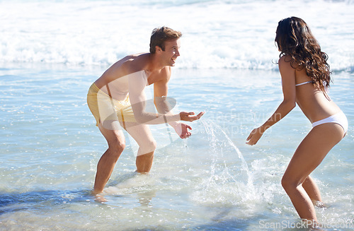 Image of Water, splash and happy couple playing on beach for holiday adventure together on tropical island nature. Love, man and woman on ocean vacation with playful fun, romance and smile on travel in Hawaii