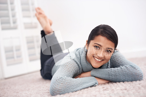 Image of Portrait of girl on carpet with smile, relax and weekend break to unwind in living room at house. Face of woman lying on floor of apartment to chill with happiness, peace and calm in lounge at home.