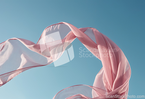Image of Flying pink fabric wave on blue sky background and illuminated b