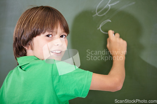 Image of Portrait, happy and boy writing on a chalkboard for child development, confidence and art for learning. Academic, creative and kid student drawing in the classroom with face, school and answers