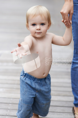 Image of Baby, walking and mother outdoor for development with portrait, curiosity or holding hands in backyard of home. Toddler, child and relax on wooden deck for wellness, milestone and exploring in garden