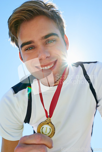 Image of Winner, man and sports medal for achievement, success and portrait in running competition. Happy face of a runner or athlete with red and gold prize, contest or marathon on a blue sky and lens flare