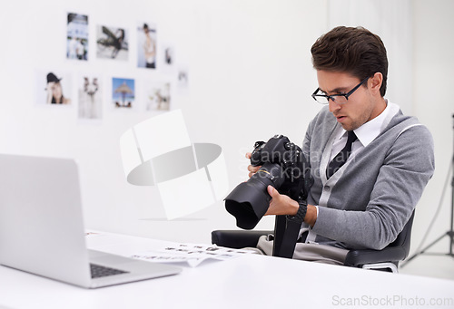 Image of Man, camera and photography in office with laptop, checking image batch and creative in workplace. Person, thinking and glasses for vision, technology and focus in agency with professional career
