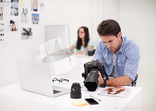 Image of Camera, office and photographer looking at photoshoot in a studio or workshop for production. Creative, photography and young artist with dslr equipment for picture inspection in modern workplace.