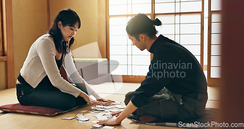 Image of Man, woman and game with Japanese cards on floor in challenge, contest or problem solving with clue. People, couple and karuta for competition with paper, reading or play together to relax in home