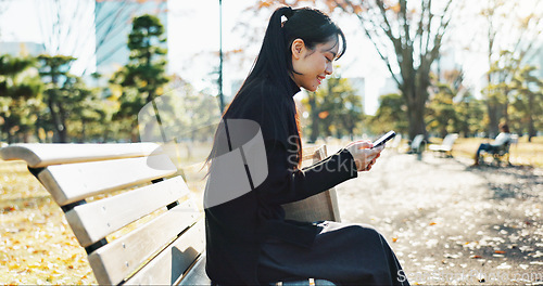 Image of Happy asian woman, phone and typing on park bench for social media, communication or networking. Female person smile in relax on mobile smartphone for online search, streaming or reading in nature